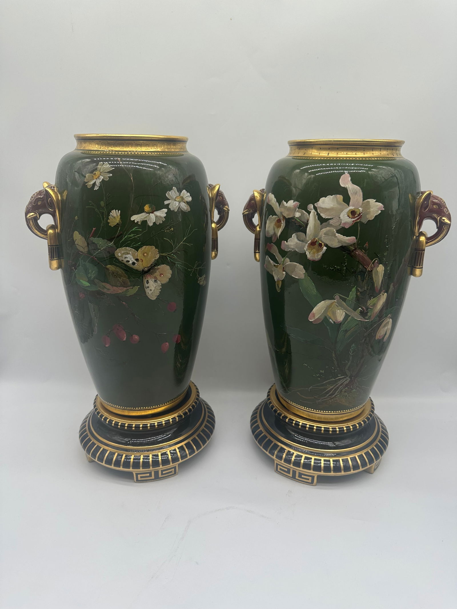 A monumental pair of Mintons glazed earthenware vases: date code for 1876 Flanked by stylized elephant and ring handles, decorated with flora and butterflies, one signed R. Pilsbury, on circular foot, impressed MINTONS, date cypher and 1744, gold painted
