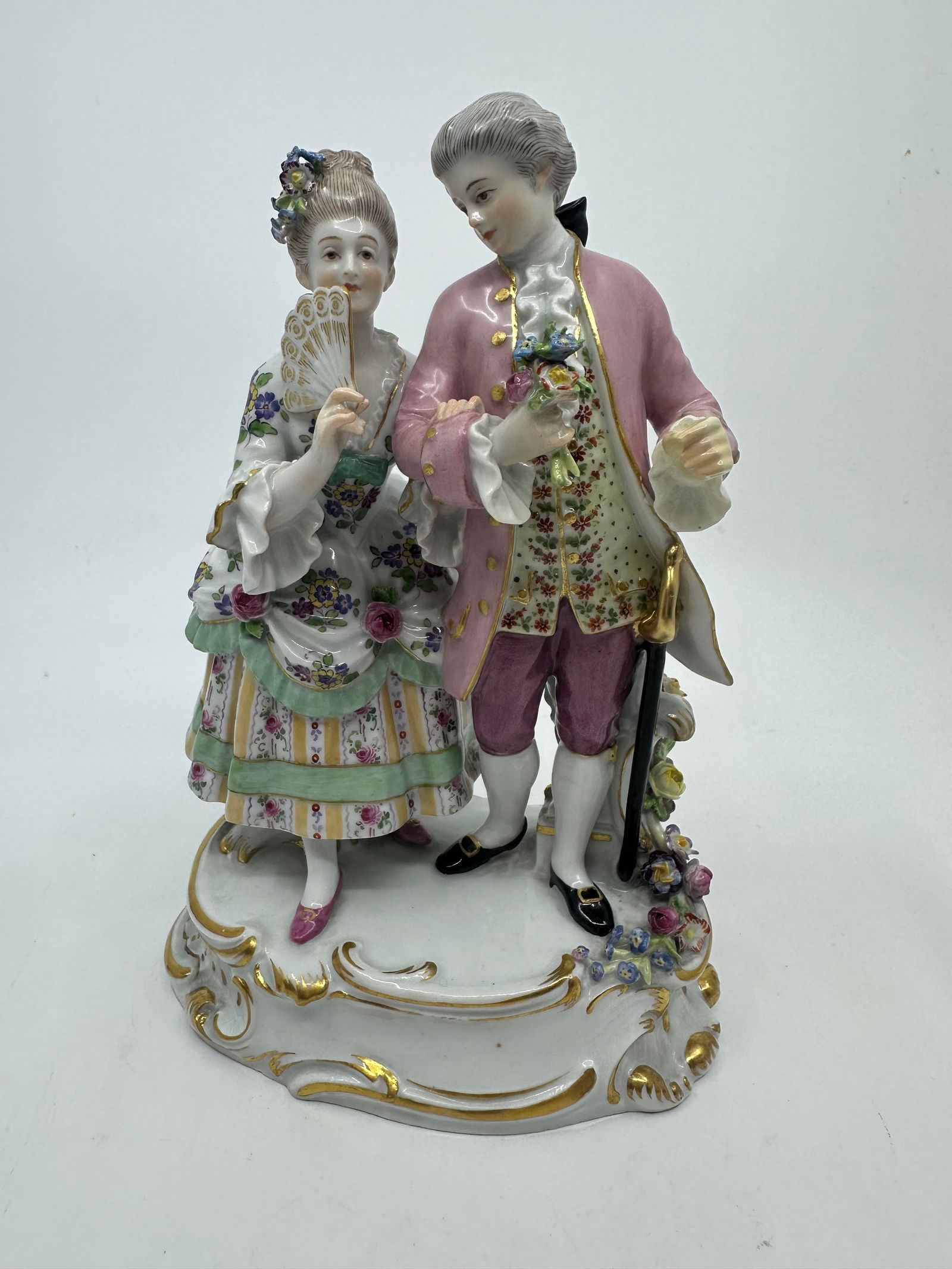 ANTIQUE MEISSEN PORCELAIN GROUP OF COUPLE: A Meissen Porcelain Figural Group Early 20th century, modeled to show a gentleman and a lady in 18th century attire, with crossed swords in underglaze blue to the underside, Incised O162 and Pressnumm