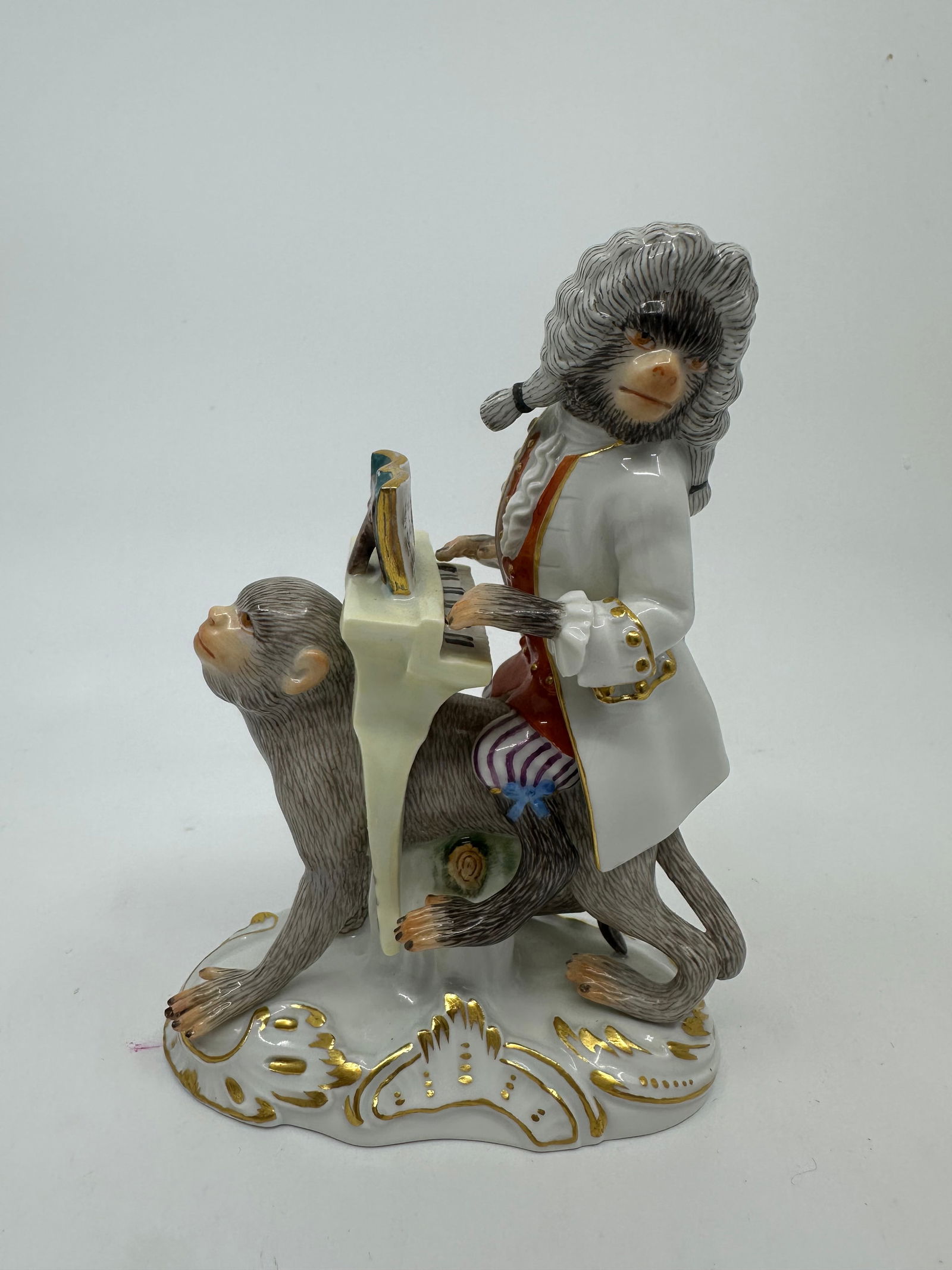 Meissen porcelain monkey band figure: monkey band, Meissen, around 1880, after the model of 1745, monkey playing piano on a back,finely and colorful painted, gold heightened ,Meissen-brand mark with accentuated knob, approx. 12x11x5 ,5 cm
