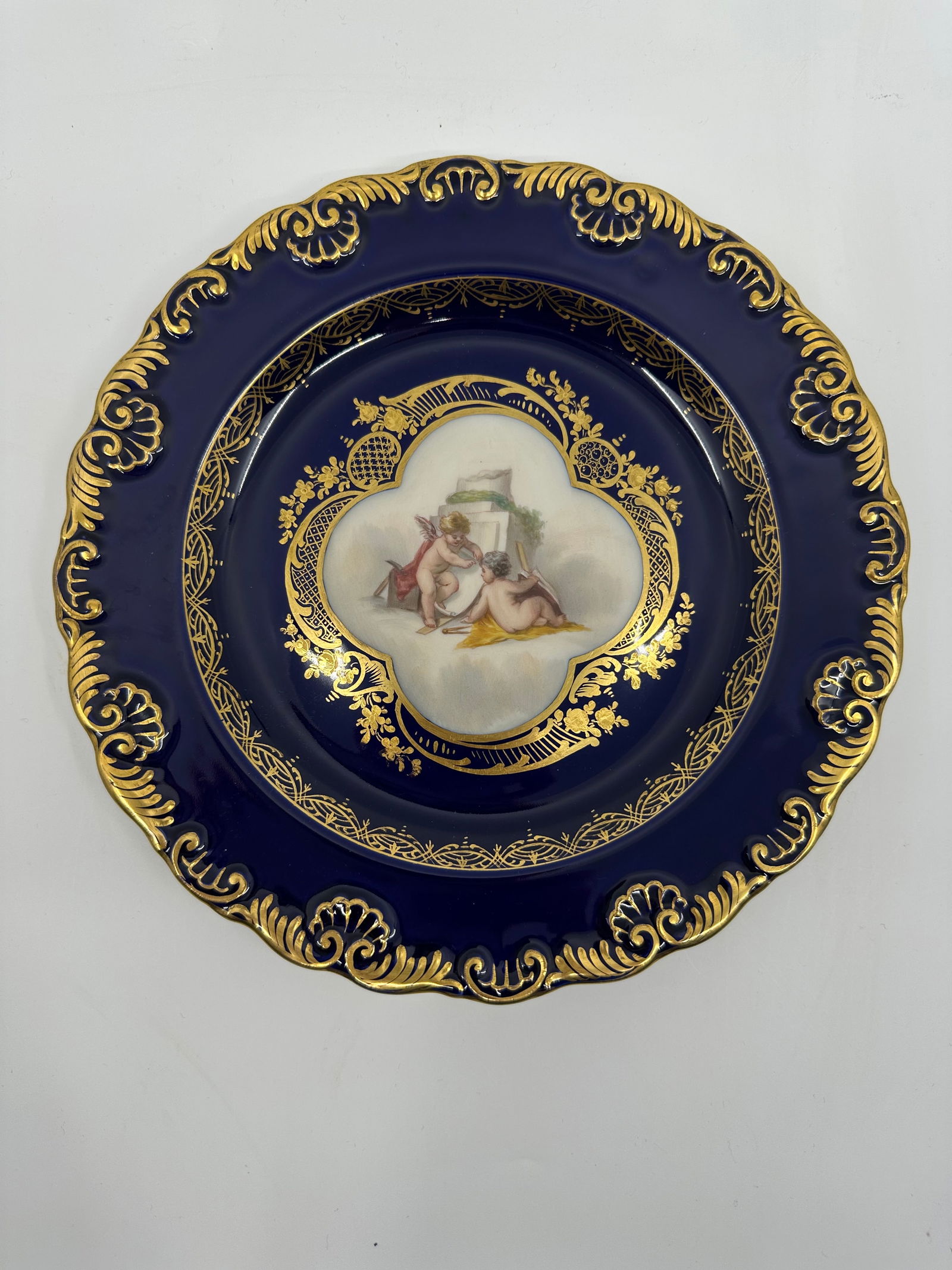 ANTIQUE MEISSEN PORCELAIN COBALT PLATE: ANTIQUE MEISSEN PORCELAIN COBALT PLATE. LATE 19TH, BLUE CROSSED SWORDS MARK, IMPRESSED marksFinely painted putto scenes, gilt line rim 9 in. (23.4 cm.) diameter