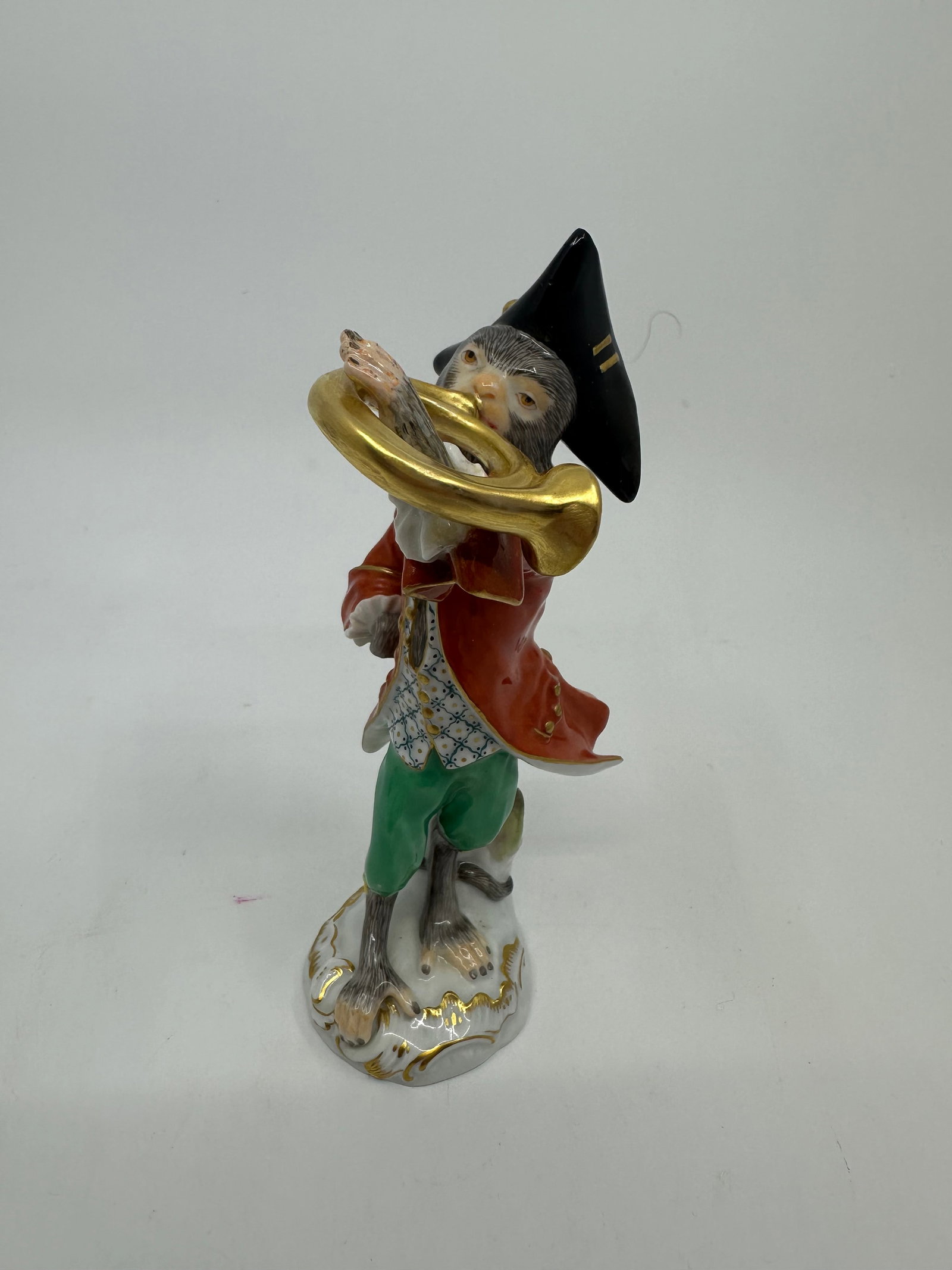 Meissen porcelain monkey band figure: Meissen hand-painted porcelain figure, the French horn player from the monkey band, after the model by Johann Joachim Kandler (German, 1706-1775), depicted in a black tricorne hat and red coat, on a p