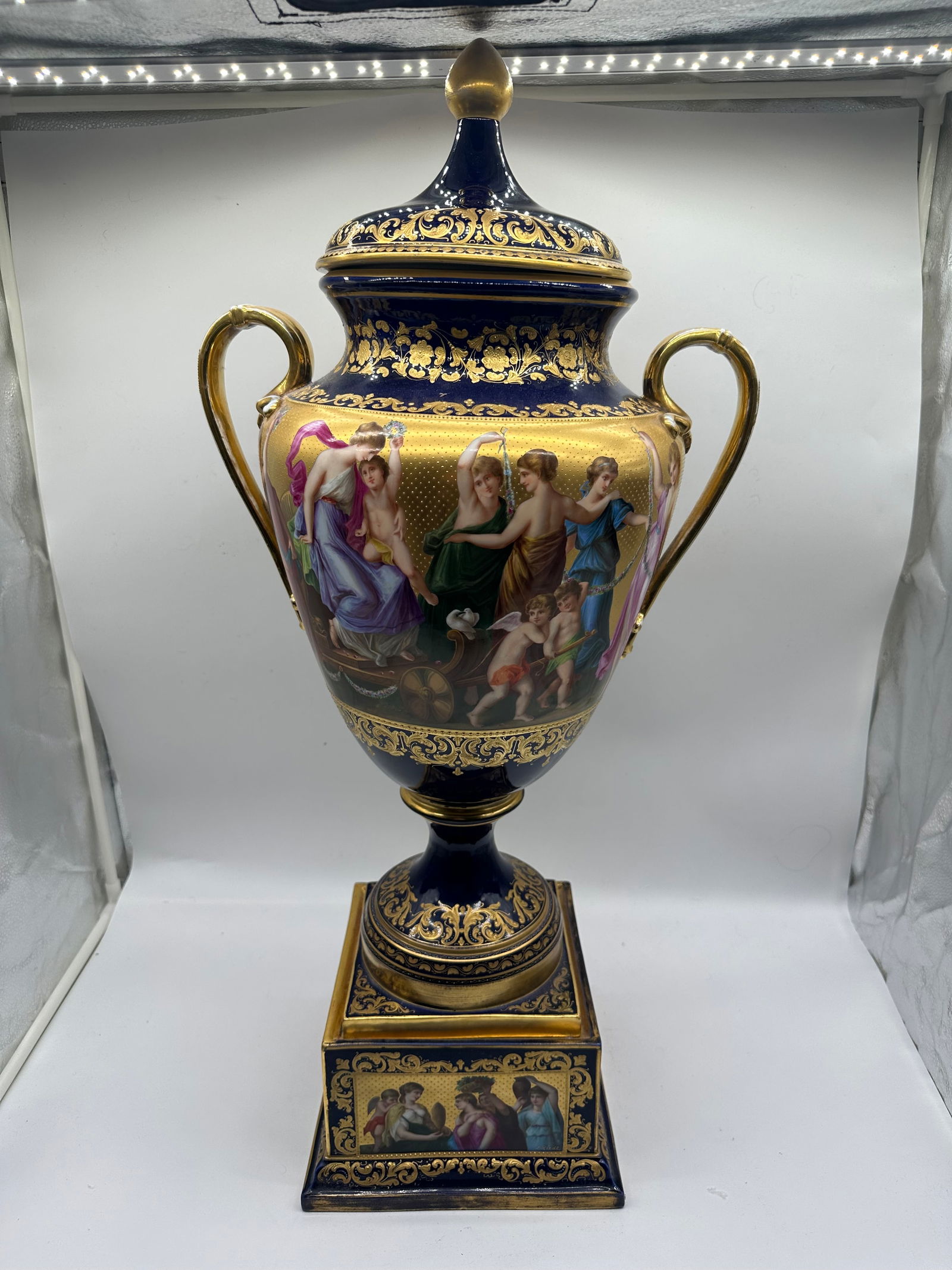 Monumental Antique Royal Vienna Mythological Vase: VIENNA PORCELAIN BLUE-GROUND TWO-HANDLED VASE AND COVERCIRCA 1900, UNDERGLAZED BLUE SHIELD MARK, SIGNED 'J. Riedl'Each painted with a continuous scene of mythological scenes in landscape against a gol