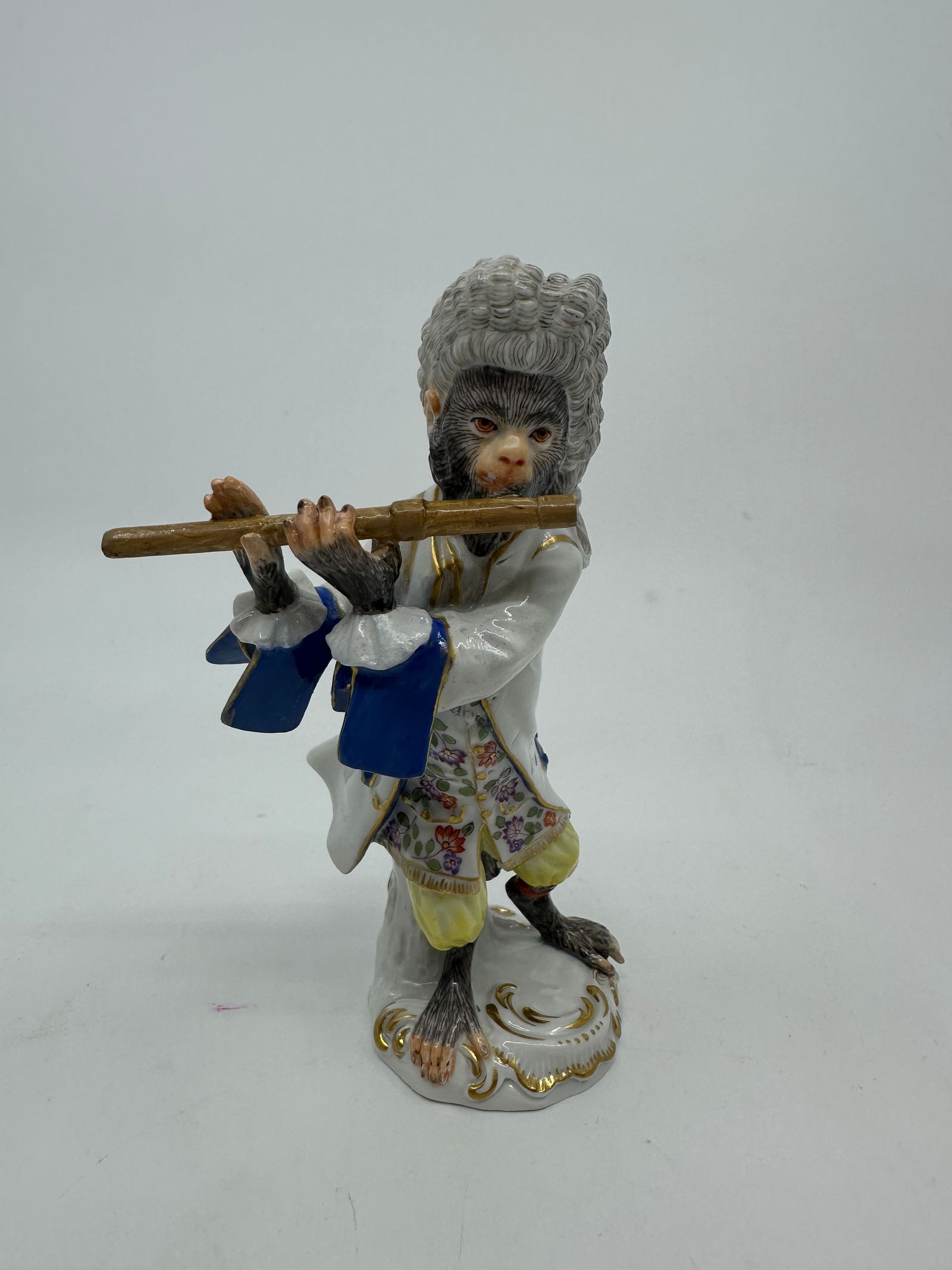 Meissen porcelain monkey band figure: Meissen (German) early 20th century porcelain monkey band flute player figurine. Wearing white coat, blue cuffs and pockets, flowered waistcoat, both with gold buttons, and yellow breeches. Marked wit