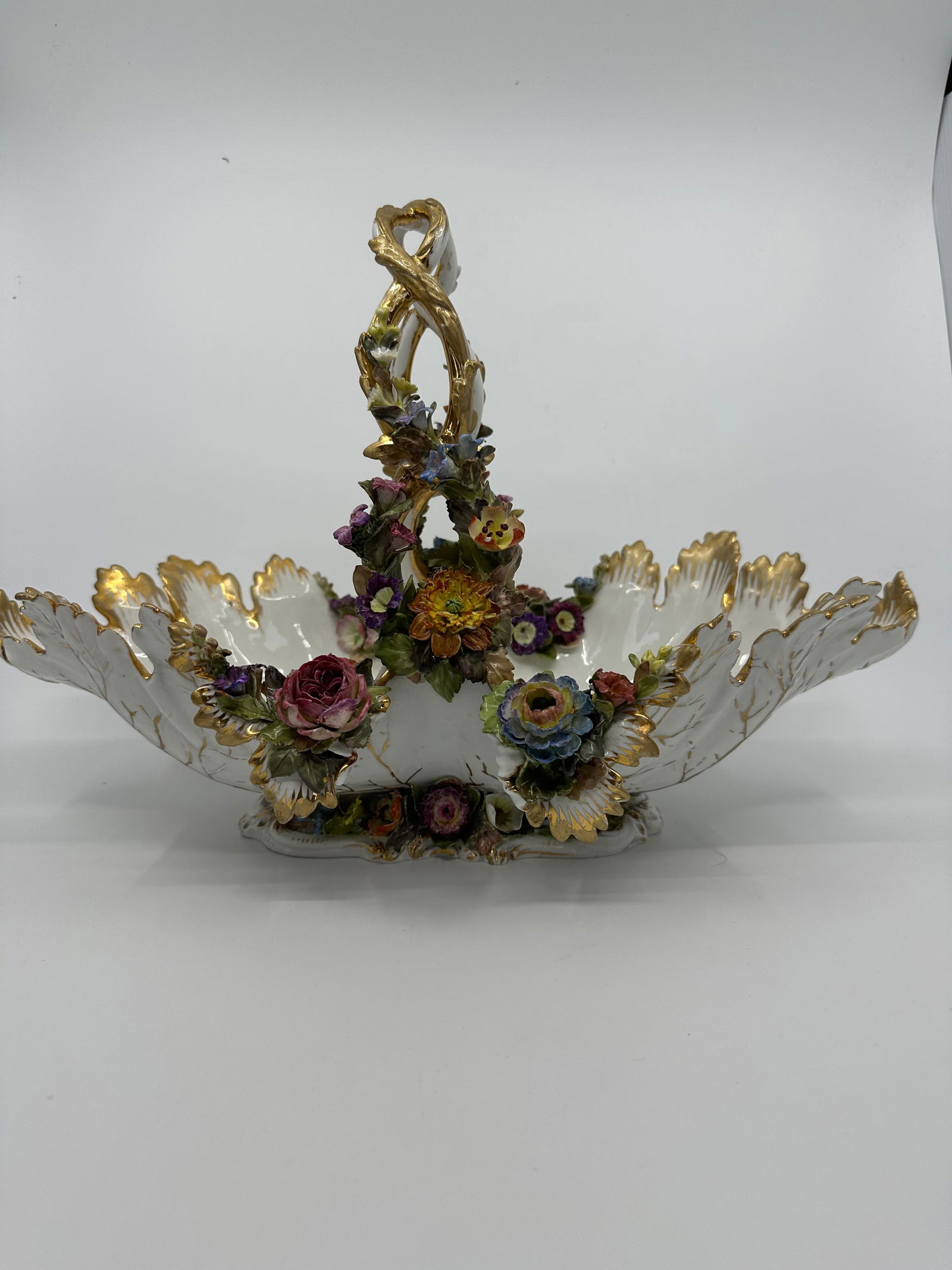 Antique meissen flower basket: Description A beautiful antique Meissen floral porcelain handled basket. Has vine form handle and and figural leaves bowl. Hand painted floral bouquets to bowl interior. Figural leaves throughout. Hol