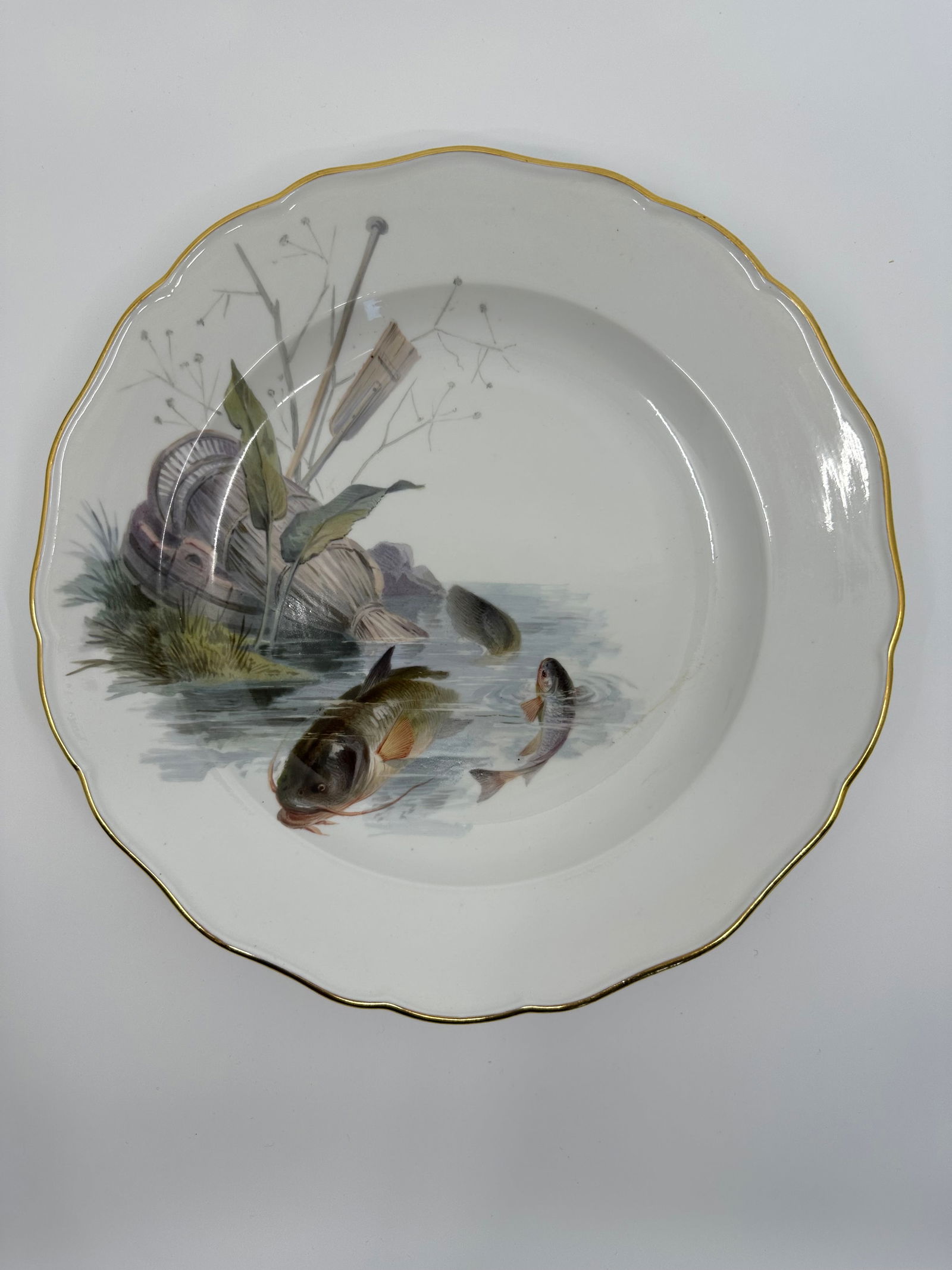 Antique Meissen porcelain fish plate: Each plate is individually decorated with a different type of fish swimming with varied items in the background including, ships, fishing boats, barrels, dock fragments, baskets, and landscape. All pi