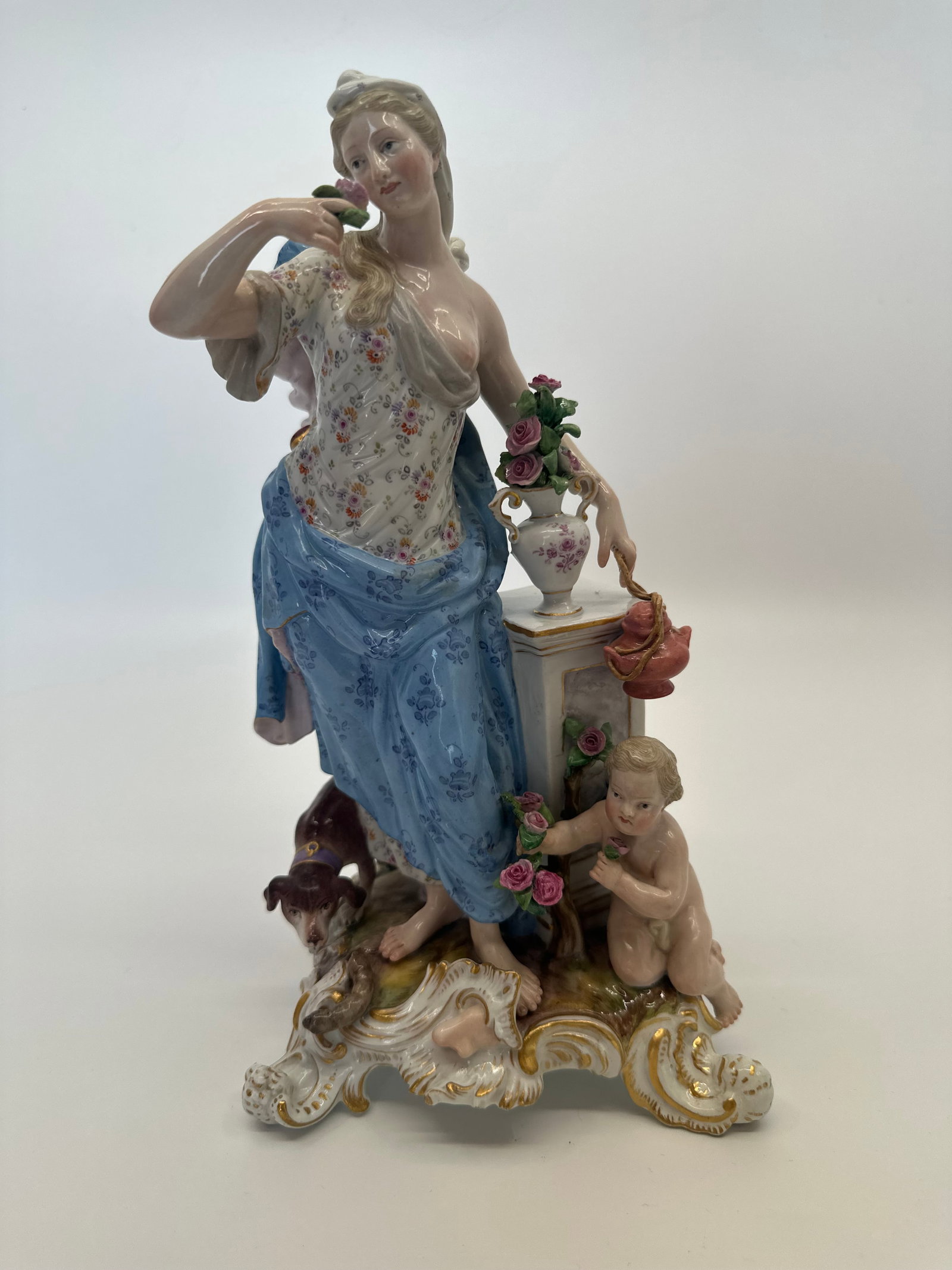 Meissen Emblematic of Senses Figurine "Smell" 19th C: This Figure came from a selection of five representing senses that the Meissen Factory made. This one is Representing "Smell". The Woman and Putti are smelling Flowers whilst a Hound looks like he's s