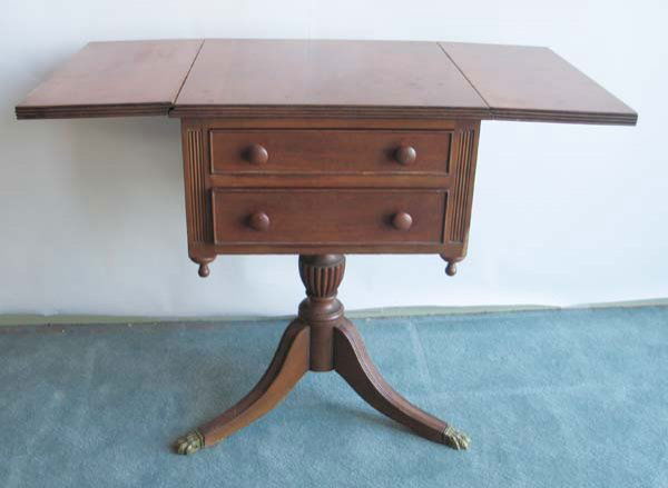 394: A Mahogany Duncan Phyfe-style: A Mahogany Duncan Phyfe-style two drawer workstand with drop leaves, reeded edging to the top, wooden pulls on the drawers, a reeded urnform column.