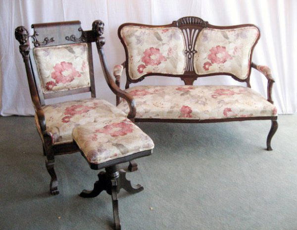 A Parlor Grouping to Include: an Art Nouveau mahogany settee with upholstered back pads separated by a carved and pierced splat, curved arms, arm supports and legs, upholstered elbow pads and seat; a mahogany open arm chair with r
