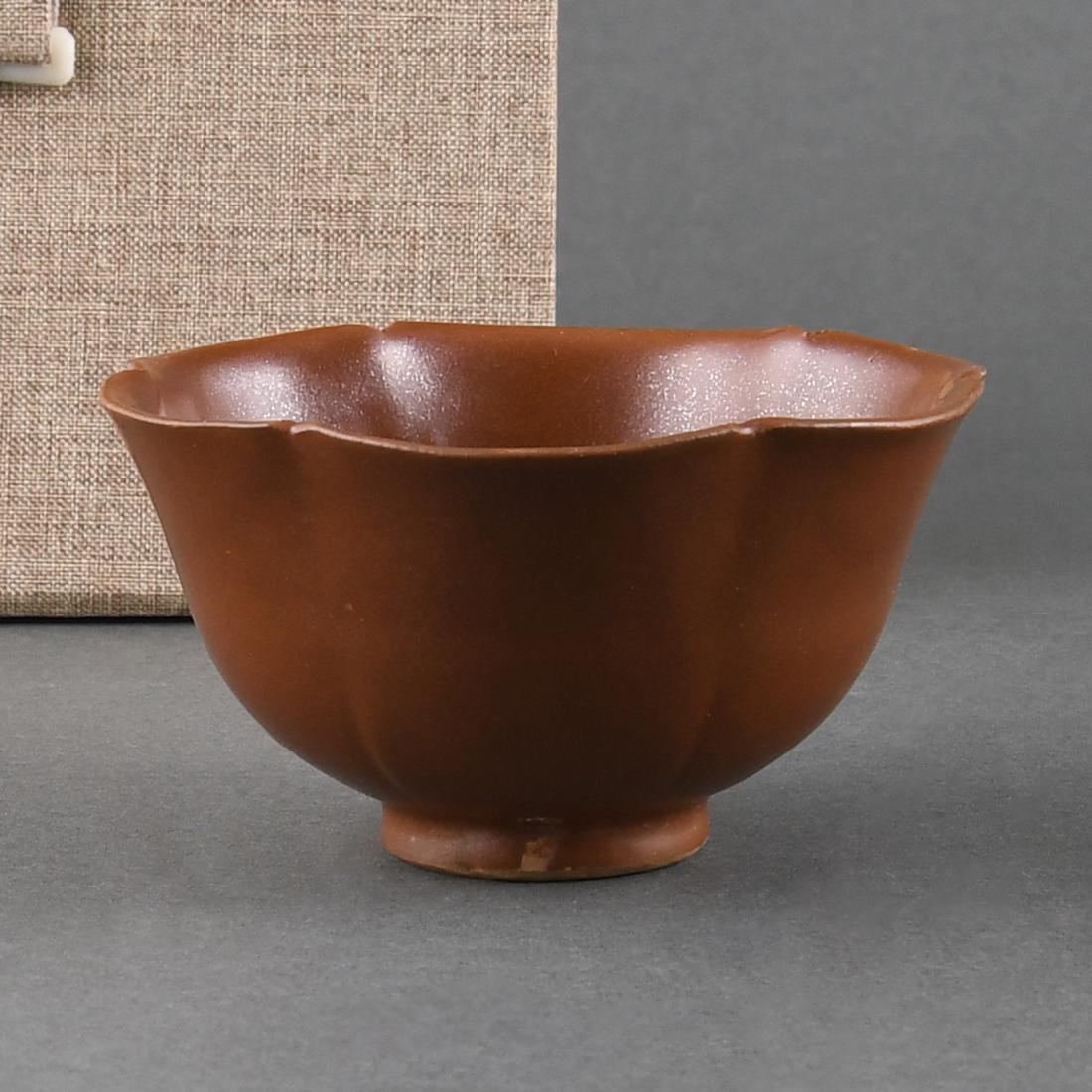 A 'YAOZHOU' PERSIMMON-GLAZED CUP: A 'YAOZHOU' PERSIMMON-GLAZED CUPDia:10.4cm, H:5.5cmFinely potted, the gently rounded sides rising from a tall straight foot to an everted hexafoil rim, covered overall in a lustrous persimmon glaze.