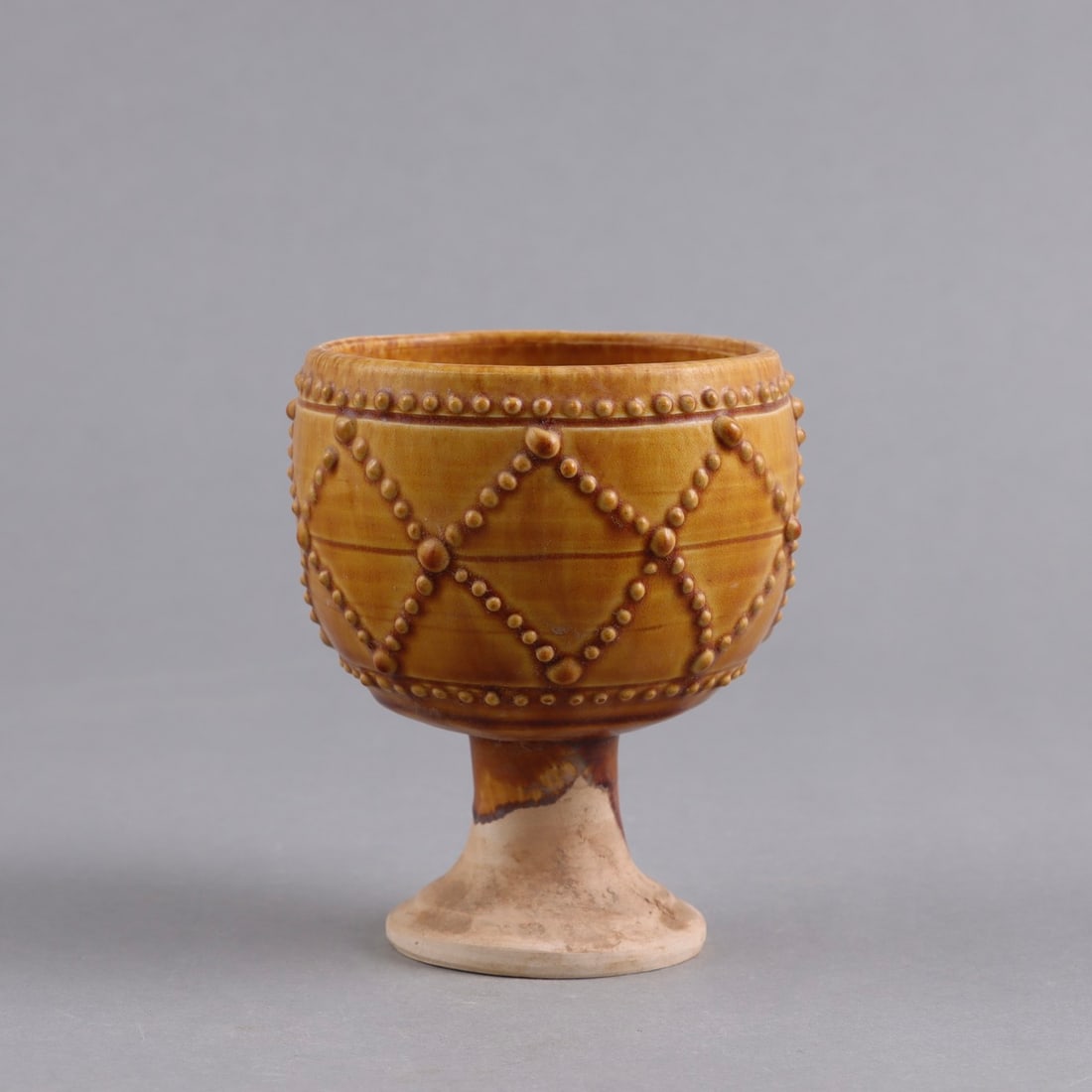 A MOLDED 'GONGXIAN' AMBER-GLAZED STEM CUP (1 of 9)
