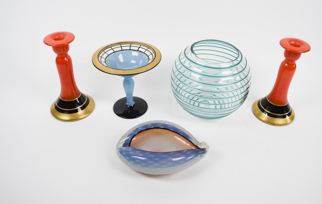 Lot of Art Glass Murano Style Candlesticks, bowls & cup: Lot of various artistic glass objects. Two red candlesticks, a blue transparent spherical vase, translucent blue martini glass, and a large cowry shell. Candlesticks: 8.5"; vase 8.5"dia . 5000-0082-5