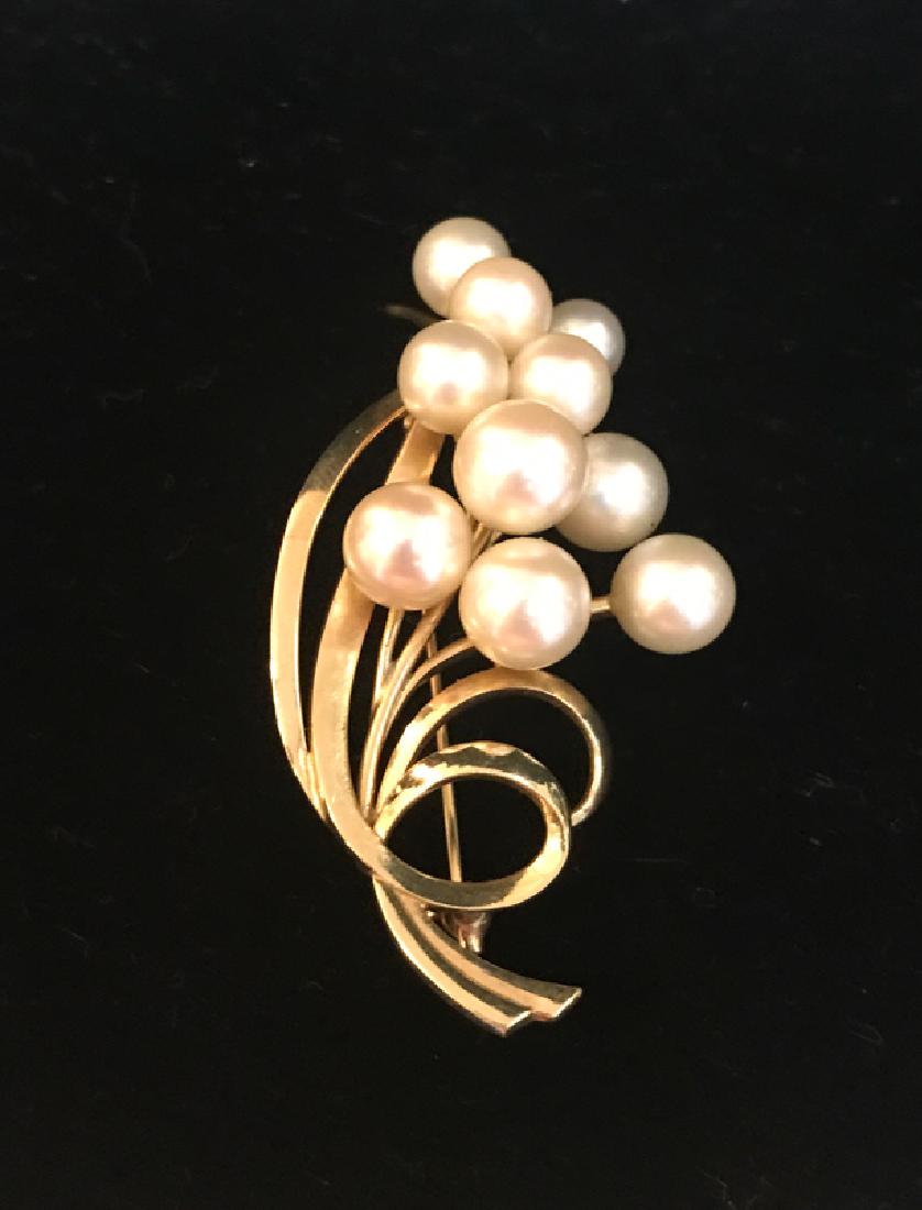 14K Mikimoto Yellow Gold and Pearl Brooch: A 14 Karat yellow gold and pearl brooch. Cluster of 10 cultured pearls mounted on a naturalistic setting of stems and long leaves. Approximately 57 x 31 mm, 13.28 g. Pearls range in size from 4-5mm. S
