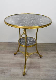 Empire Style Gueridon: Gilt bronze and marble circular top raised on sabre form supports hung with rings joined by a shelf stretcher and ending in hoof feet. Height 29" diameter 22.5"