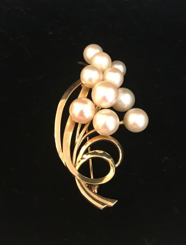 14K Mikimoto Yellow Gold and Pearl Brooch: A 14 Karat yellow gold and pearl brooch. Cluster of 10 cultured pearls mounted on a naturalistic setting of stems and long leaves. Approximately 57 x 31 mm, 13.28 g. Pearls range in size from 4-5mm. S
