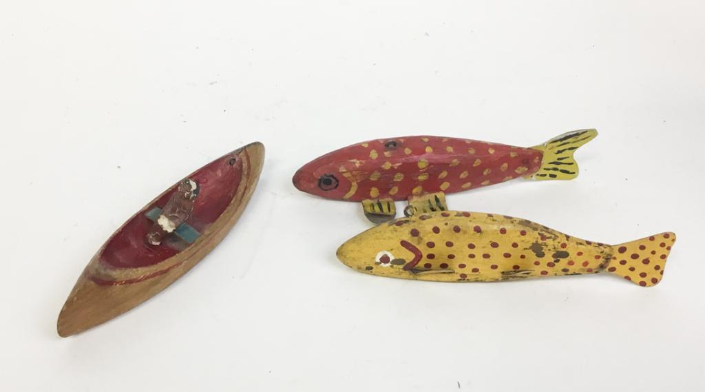 Folk Art Fishing Lures and Figure in Canoe: Two early fishing lures. One with red decoration on a yellow background and one with yellow decoration on a red background. Also included in this lot is an American Indian in a canoe. Carved from wood
