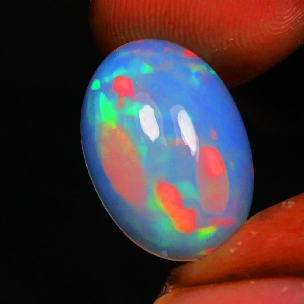 4.87 Ct Natural Multi-Color Fire Opal Loose Stone: Weight - 4.87 Ct / Size - 16.90 x 12.10 x 6.00 mm / Shape - Oval Cab / Color - Multicolor / Clarity - Translucent / Origin - Ethiopia / Treatment - None
