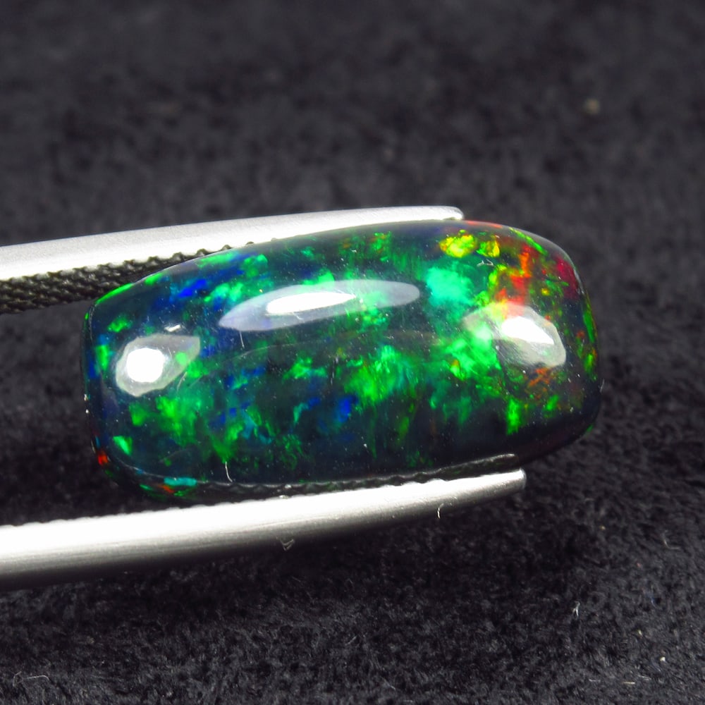 4.85 Ct Natural Black Flashing Fire Opal Cushion Cab: Weight - 4.85 Ct / Size - 18.00 x 9.40 x 5.60 mm / Shape - Cushion Cab / Color - Black / Clarity - Translucent / Origin - Ethiopia / Treatment - Color Smoked