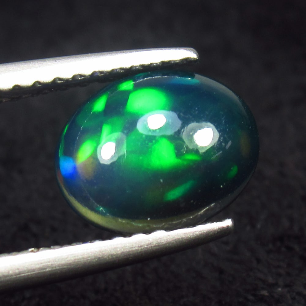 1.08 Ct Natural Black Flashing Fire Opal Oval Cab: Weight - 1.08 Ct / Dimensions - 9.00 x 7.20 x 3.70 mm / Shape - Oval Cab / Color - Black / Clarity - Translucent / Origin - Ethiopia / Treatment - Color Smoked