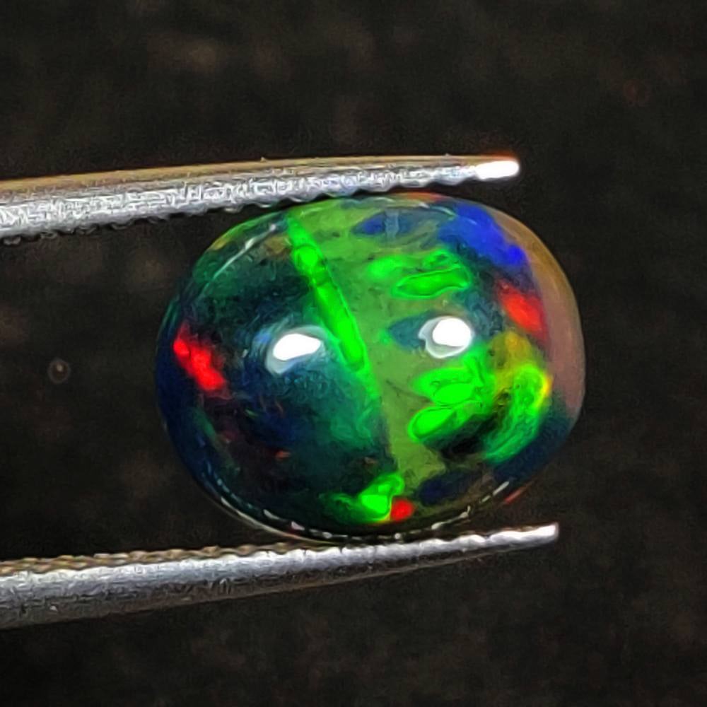 1.64 Ct Natural Black Flashing Fire Opal Oval Cab: Weight - 1.64 Ct / Dimensions - 10.00 x 8.20 x 4.50 mm / Shape - Oval Cab / Color - Black / Clarity - Translucent / Origin - Ethiopia / Treatment - Color Smoked