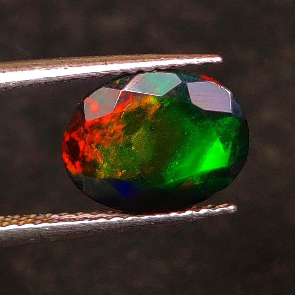 1.49 Ct Natural Black Flashing Fire "Shadowfire" Opal Oval Cut: Weight - 1.49 Ct / Dimensions - 10.00 x 7.80 x 4.50 mm / Shape - Oval Cut / Color - Black / Clarity - Translucent / Origin - Ethiopia / Treatment - Color Smoked