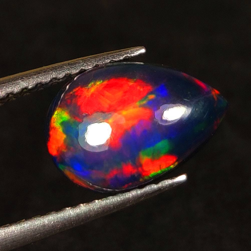 1.26 Ct Natural Black Flashing Fire Opal Pear Cab: Weight - 1.26 Ct / Dimensions -10.40 x 7.30 x 3.70 mm / Shape - Pear Cab / Color - Black / Clarity - Translucent / Origin - Ethiopia / Treatment - Color Smoked