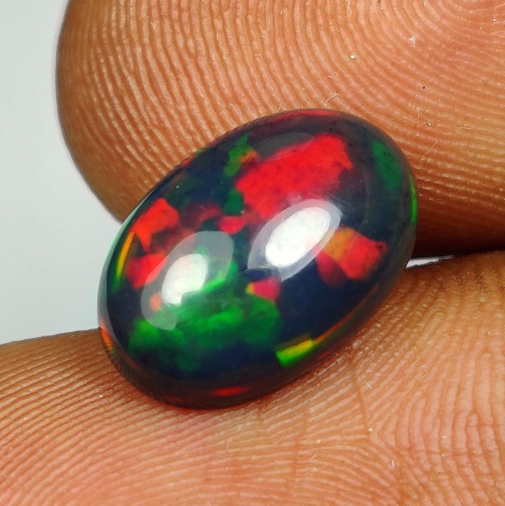 1.95 Ct Natural Black Flash Fire Opal OVal Cab: Weight - 1.95 Ct / Size - 12.40 x 8.40 x 4.20 mm / Shape - OVal Cab / Color - Black / Clarity - Translucent / Origin - Ethiopia / Treatment - Color Smoked