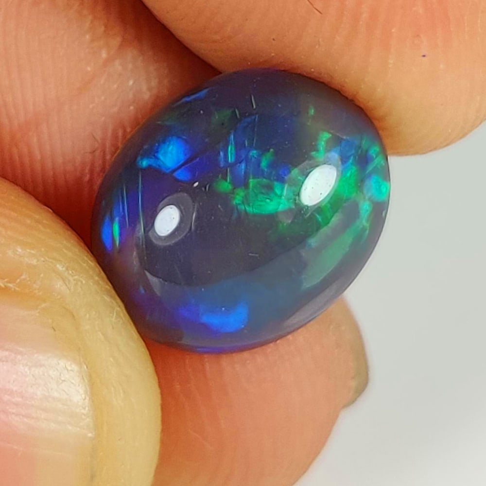 2.19 Ct Natural Black Flashing Fire Opal Oval Cab: Weight - 2.19 Ct / Dimensions - 11.00 x 9.10 x 4.50 mm / Shape - Oval Cab / Color - Black / Clarity - Translucent / Origin - Ethiopia / Treatment - Color Smoked