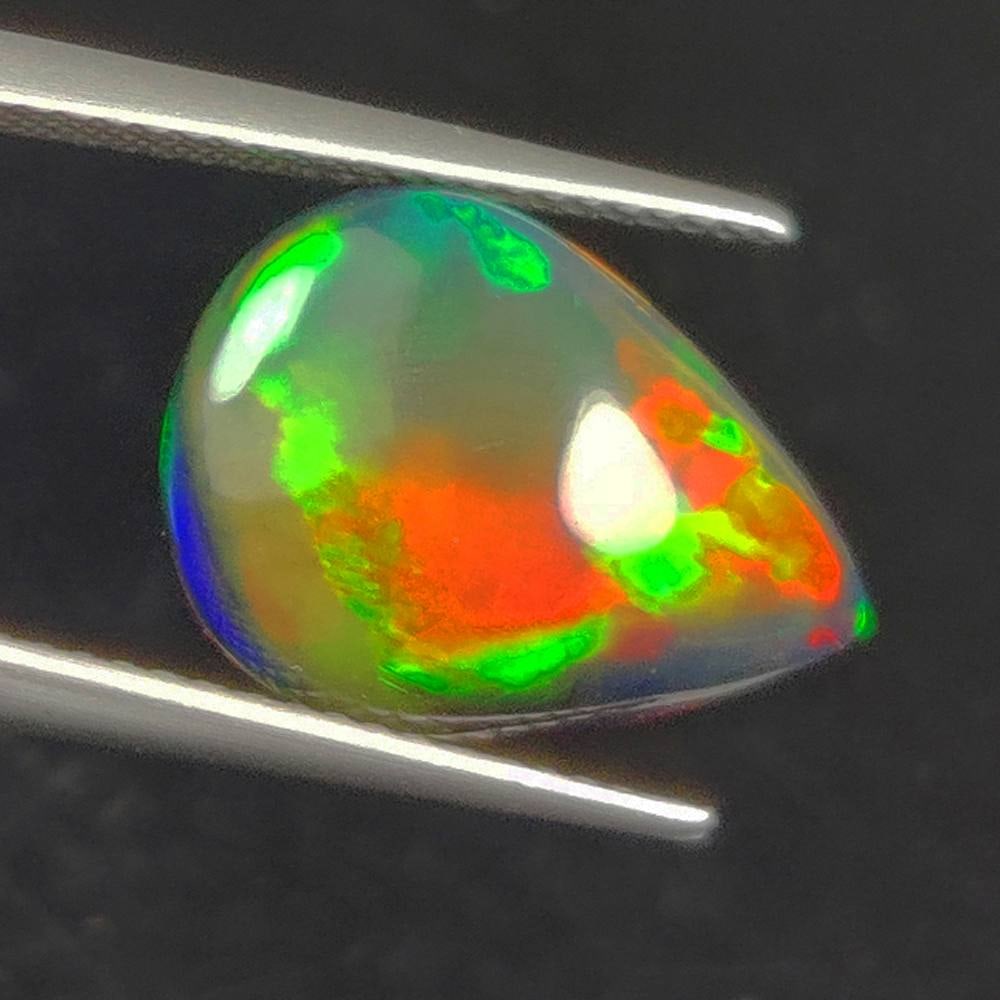 4.64 Ct Natural Black Flashing Fire Opal Pear Cab: Weight - 4.64 Ct / Dimensions - 15.90 x 11.60 x 5.90 mm / Shape - Pear Cab / Color - Black / Clarity - Translucent / Origin - Ethiopia / Treatment - Color Smoked