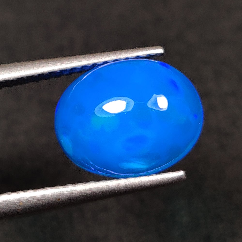 2.49 Ct Natural Blue Flashing Fire Opal Oval Cab: Weight - 2.49 Ct / Dimensions - 11.60 x 9.20 x 5.10 mm / Shape - Oval Cab / Color - Blue / Clarity - Translucent / Origin - Ethiopia / Treatment - Heated