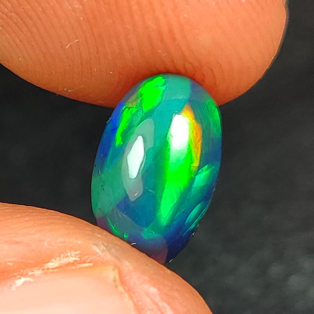 1.30 Ct Natural Black Flashing Fire Opal Oval Cab: Weight - 1.30 Ct / Dimensions - 10.10 x 6.40 x 4.30 mm / Shape - Oval Cab / Color - Black / Clarity - Translucent / Origin - Ethiopia / Treatment - Color Smoked