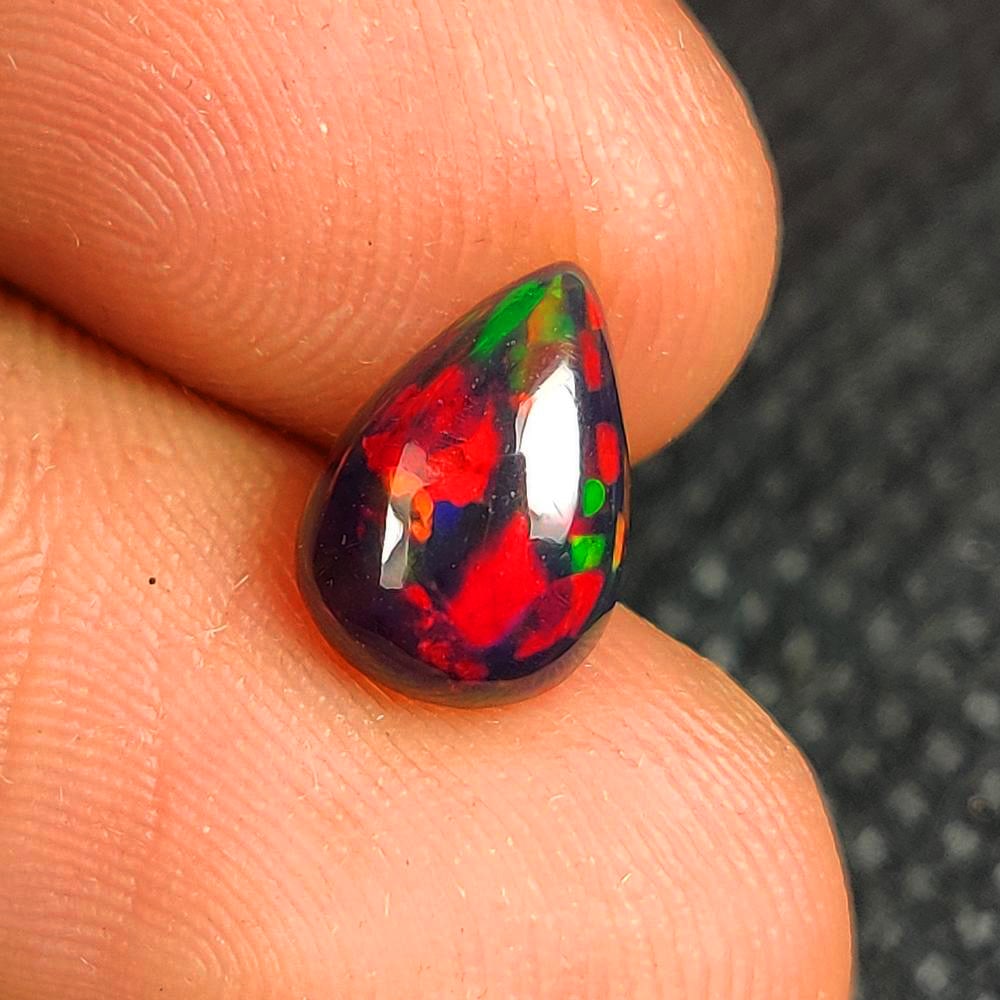 1.20 Ct Natural Black Flashing Fire Opal Pear Cab: Weight - 1.20 Ct / Dimensions - 10.10 x 7.10 x 3.80 mm / Shape - Pear Cab / Color - Black / Clarity - Translucent / Origin - Ethiopia / Treatment - Color Smoked