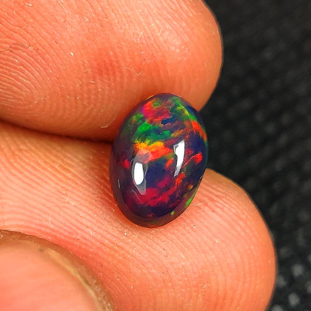 1.00 Ct Natural Black Flashing Fire Opal Oval Cab: Weight - 1.00 Ct / Dimensions - 9.30 x 6.60 x 3.40 mm / Shape - Oval Cab / Color - Black / Clarity - Translucent / Origin - Ethiopia / Treatment - Color Smoked