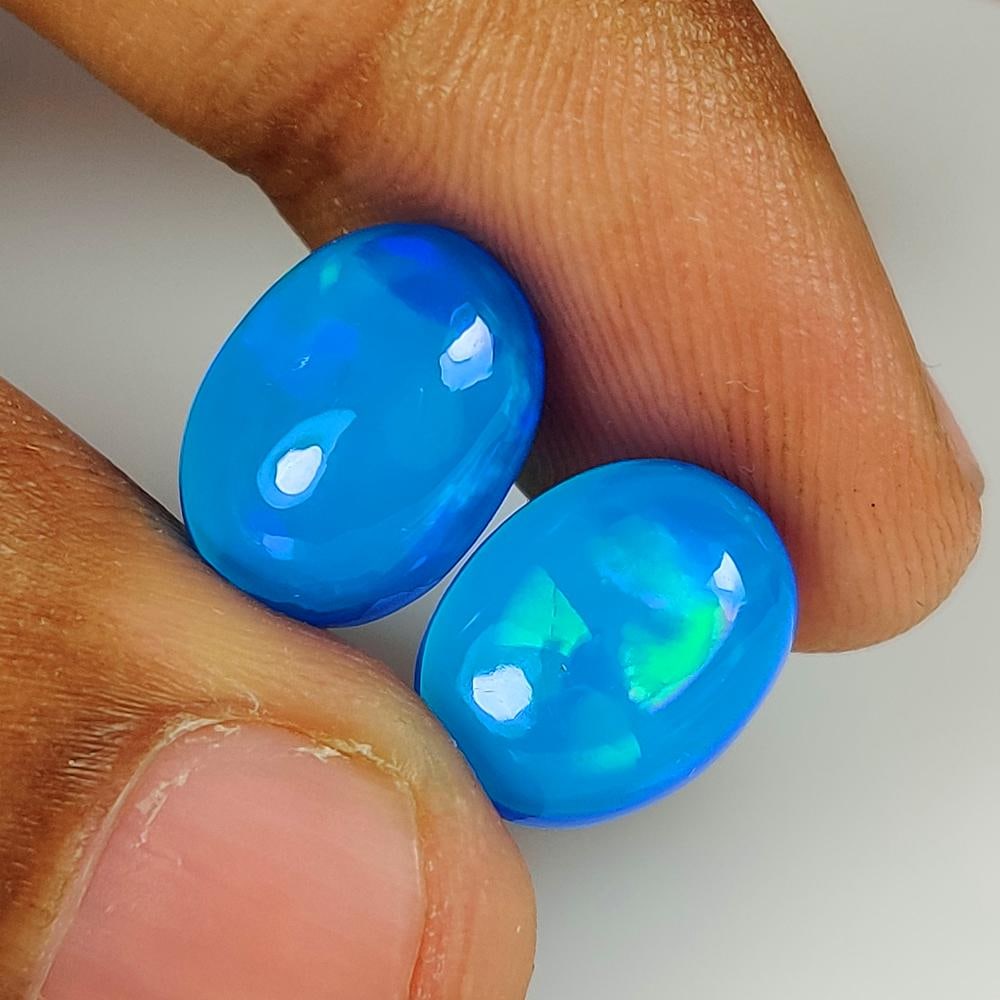 7.27 Ct Natural Blue Fire Opal Oval Cab Pair: Weight - 7.27 Ct / Size - 13.10 x 9.80 x 6.30 mm / 2 PC's / Shape - Oval Cab / Color - Blue / Clarity - Translucent / Origin - Ethiopia / Treatment - Heated