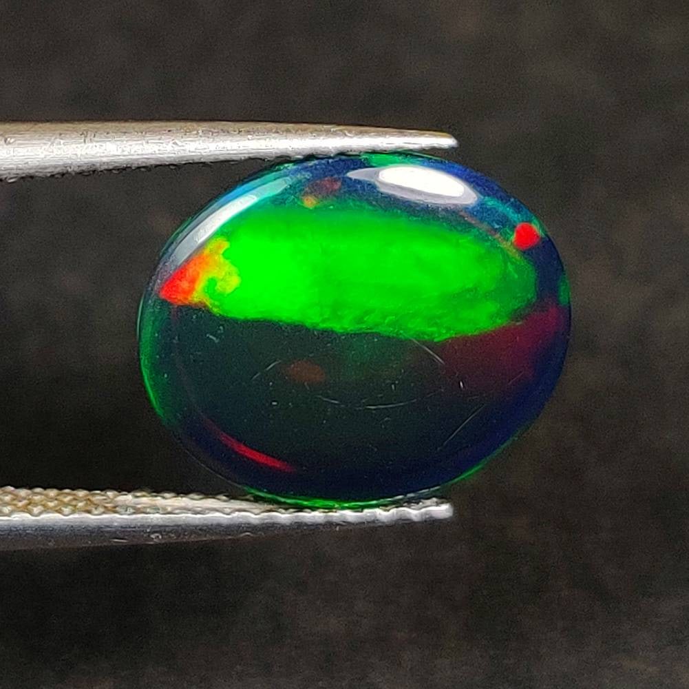 3.74 Ct Natural Black Flashing Fire Opal Oval Cab: Weight - 3.74 Ct / Dimensions - 12.70 x 10.80 x 5.90 mm / Shape - Oval Cab / Color - Black / Clarity - Translucent / Origin - Ethiopia / Treatment - Color Smoked