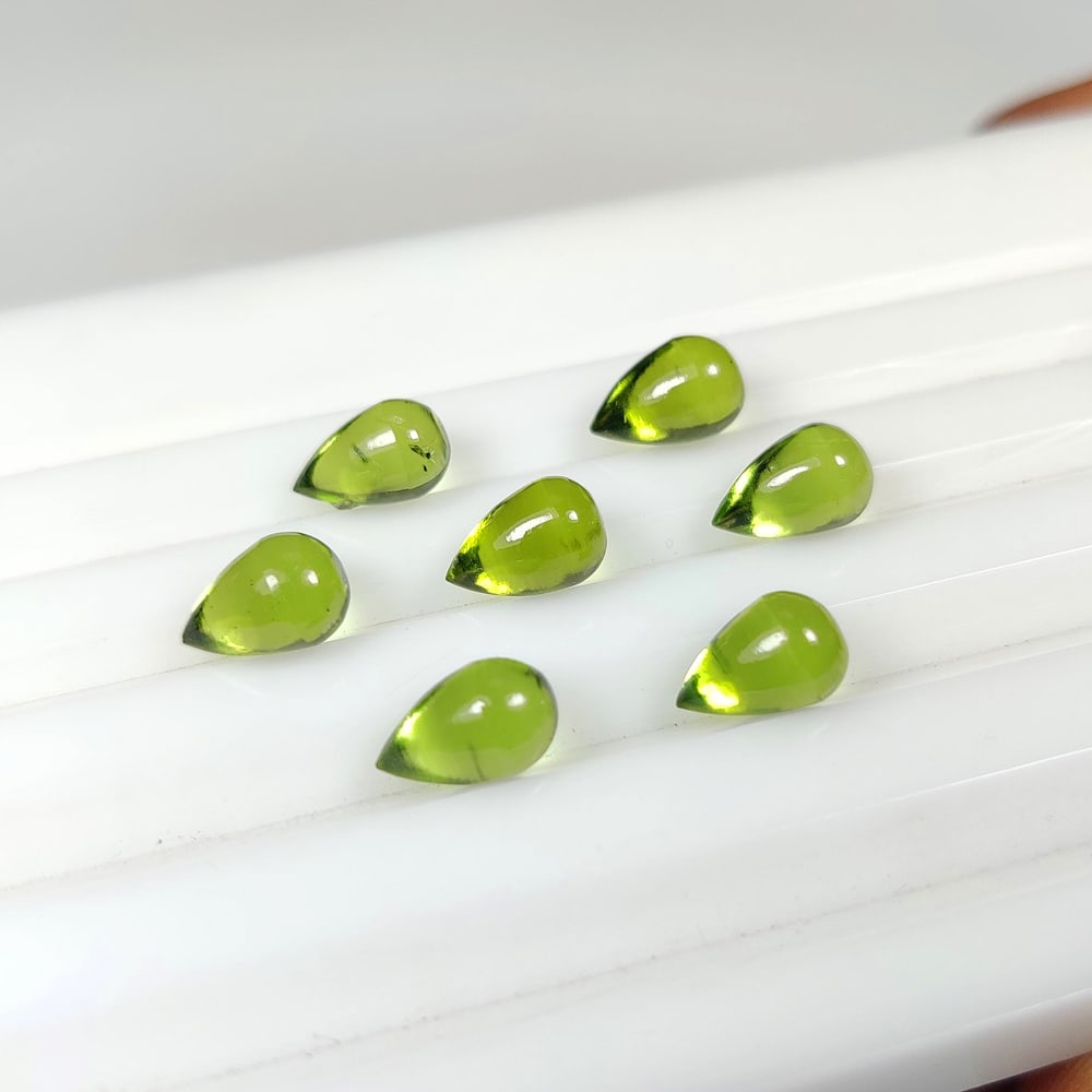 9.85 Ct Natural Green Peridot Pear Drop Set: Weight - 9.85 Ct / Size - 7.1x4.9 - 7.2x5.2 mm / 7 Pc's / Shape - Pear Drop / Color - Green / Clarity - VVS / Origin - Pakistan / Treatment - None
