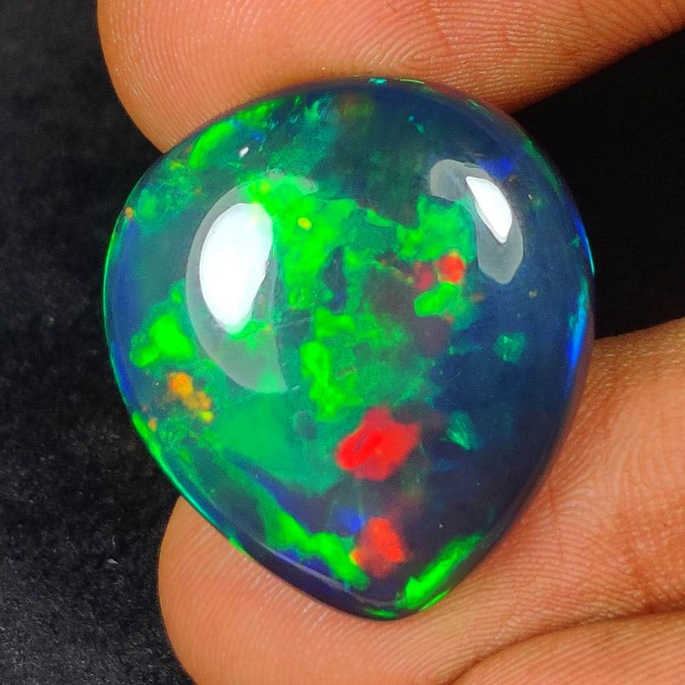 20.10 Ct Natural Black Flashing Fire Opal Pear Cab: Weight - 20.10 Ct / Dimensions - 24.00 x 20.50 x 8.70 mm / Shape - Pear Cab / Color - Black / Clarity - Translucent / Origin - Ethiopia / Treatment - Color Smoked