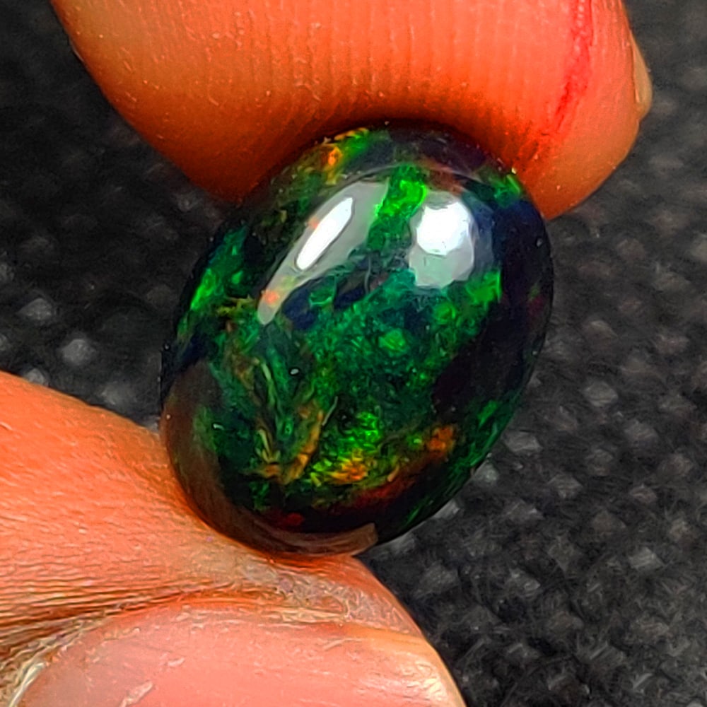 2.31 Ct Natural Black Flashing Fire Opal Oval Cab: Weight - 2.31 Ct / Size - 11.90 x 8.90 x 4.70 mm / Shape - Oval Cab / Color - Black / Transparency - Translucent / Origin - Ethiopia / Treatment - Color Smoked