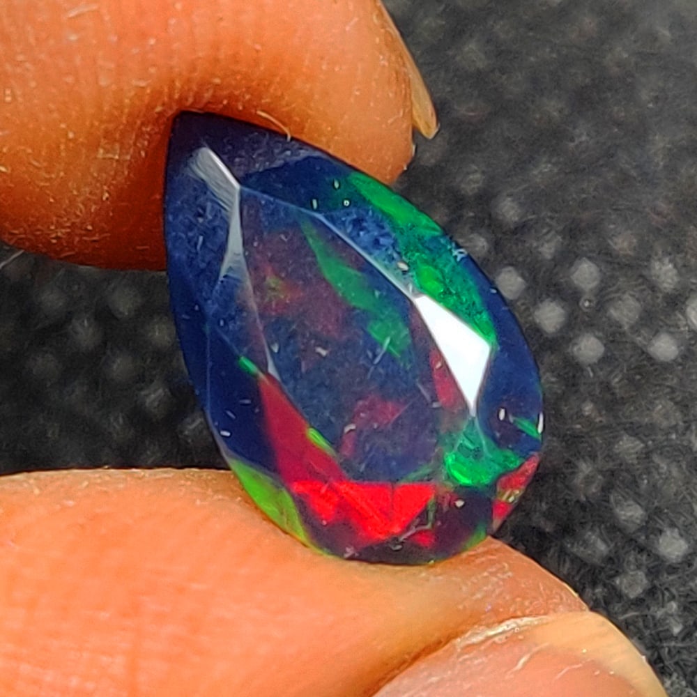 1.93 Ct Natural Black Flashing Fire Opal Pear Cut: Weight - 1.93 Ct / Size - 12.90 x 8.00 x 5.40 mm / Shape - Pear Cut / Color - Black / Transparency - Translucent / Origin - Ethiopia / Treatment - Color Smoked