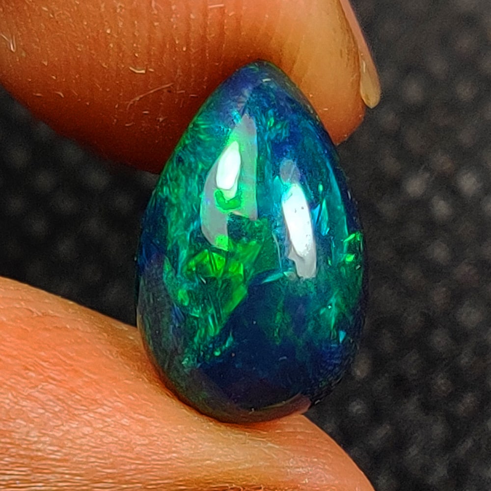 2.43 Ct Natural Black Flashing Fire Opal Pear Cab: Weight - 2.43 Ct / Size - 12.40 x 8.10 x 5.50 mm / Shape - Pear Cab / Color - Black / Transparency - Translucent / Origin - Ethiopia / Treatment - Color Smoked