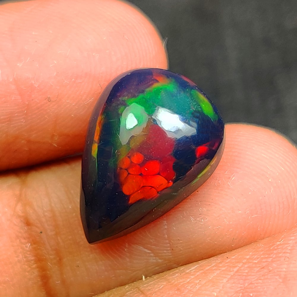 3.12 Ct Natural Black Flashing Fire Opal Pear Cab: Weight - 3.12 Ct / Dimensions - 13.50 x 9.70 x 5.70 mm / Shape - Pear Cab / Color - Black / Clarity - Translucent / Origin - Ethiopia / Treatment - Color Smoked