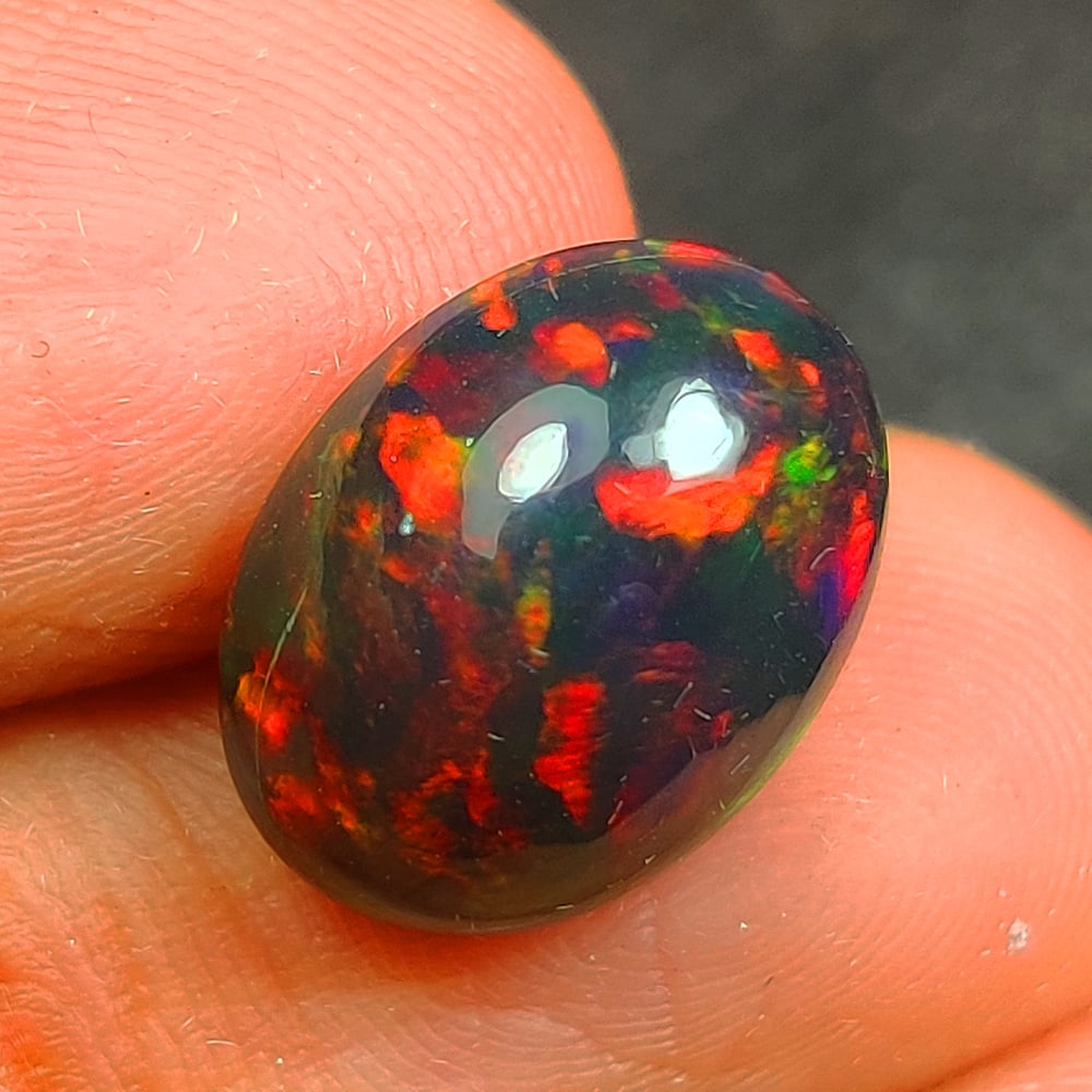 3.02 Ct Natural Black Flashing Fire Opal Oval Cab: Weight - 3.02 Ct / Size - 12.10 x 9.40 x 5.90 mm / Shape - Oval Cab / Color - Black / Transparency - Translucent / Origin - Ethiopia / Treatment - Color Smoked