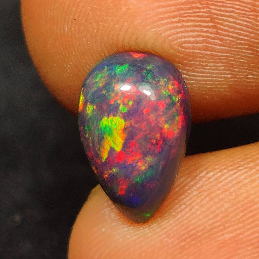 1.60 Ct Natural Black Flashing Fire Opal Pear Cab: Weight - 1.60 Ct / Dimensions - 11.20 x 7.40 x 4.50 mm / Shape - Pear Cab / Color - Black / Clarity - Translucent / Origin - Ethiopia / Treatment - Color Smoked
