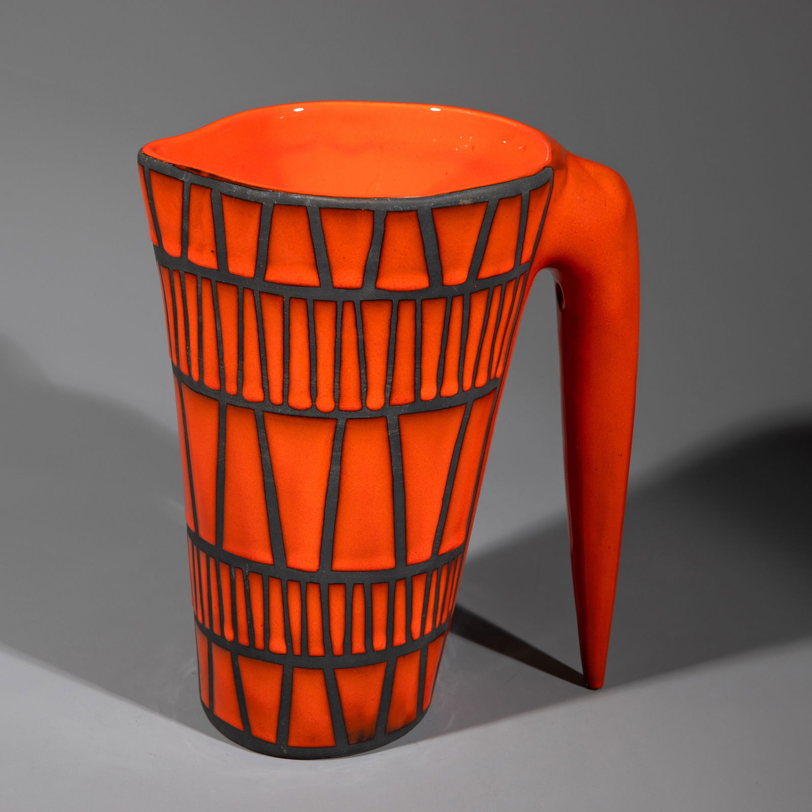 Roger Capron, Jug: Ceramic jug with an oval base and a tapered handle. The body is decorated all around with geometric red enamel decoration on a black background. 23 x 16 x 14.5 cm. Enameled signature on the underside: