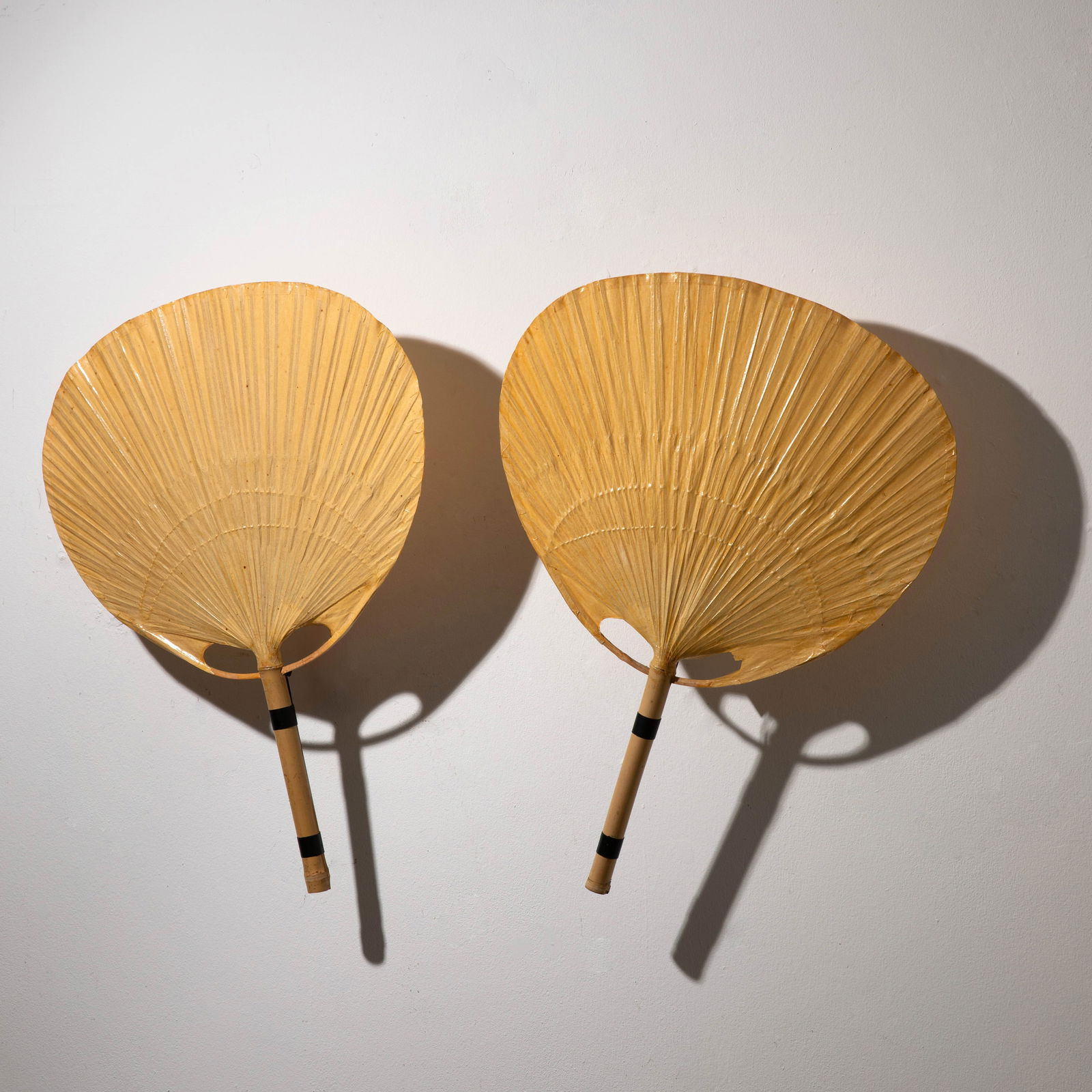 Ingo Maurer, 2 wall lights model Uchiwa: Ingo Maurer Designed in the 1970s. Manufactured by Design M. Bamboo, rice paper and metal. 75/76 x 56 x 17 cm. Both pieces are marked with a company sticker.