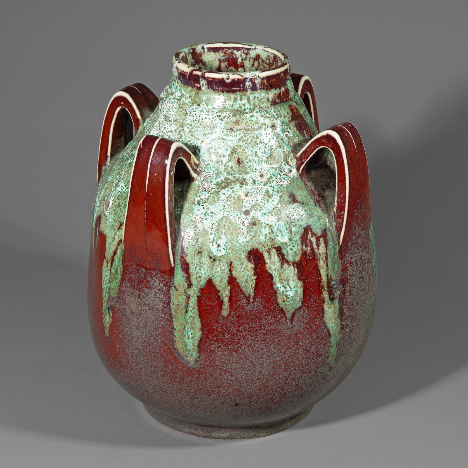 Atelier de Glatigny, Handle Vase, 1899: White porcelain, glazed, with oxblood red and feldspar green flow glaze. H. 24.5 cm. Marked: Manufacturer's mark (glazed). Art et Decoration, Bd. VI (1899), S. 138.