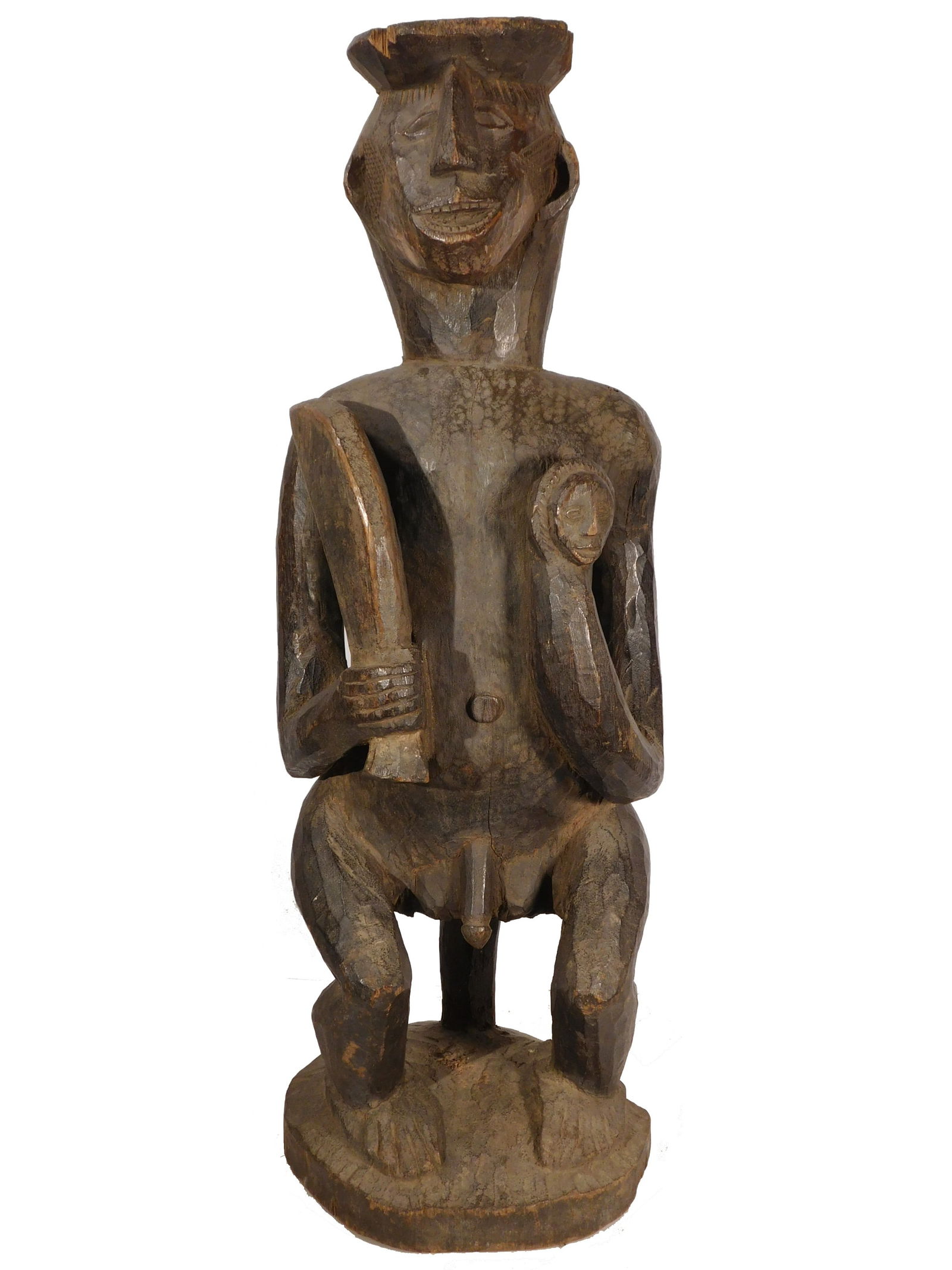 Seated Figure of a Warrior, Ibibio People, Nigeria: African Tribal Art: Ibibio People, Nigeria: Seated Figure of a Warrior, holding a knife and the head of an enemy. Carved wood, circa mid 20th century. The cheeks and back are incised with decorative
