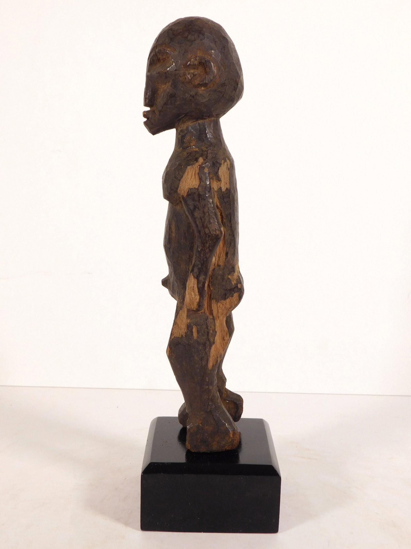African Lobi Bateba Female Figure: African Tribal Art: Lobi people, Burkina Faso: Bateba figure of a woman. 19th century, circa 1890, carved wood, mounted onto a wooden stand. The upper portion of this rough-hewn figure is patinated