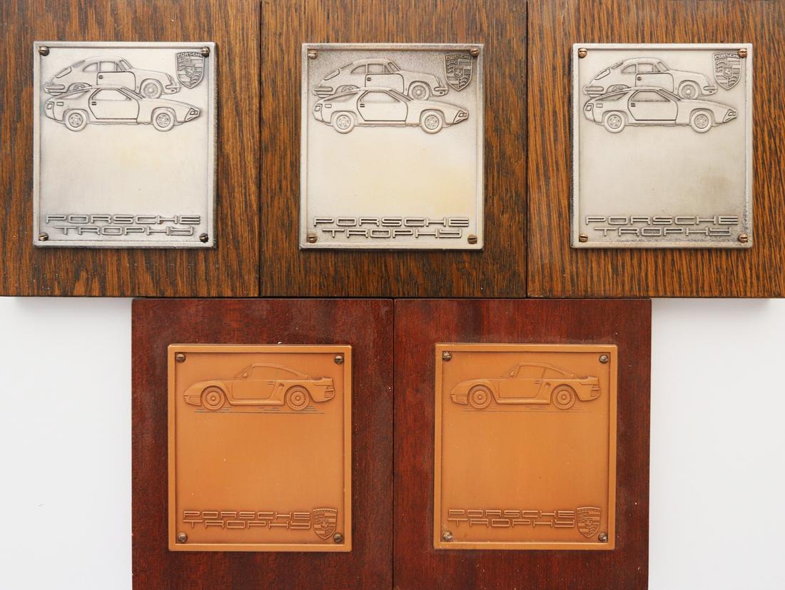 Porsche 5 x badge 'Porsche Trophy': Mounted on wooden board, in 2 different versions, 13 x 11.5 cm