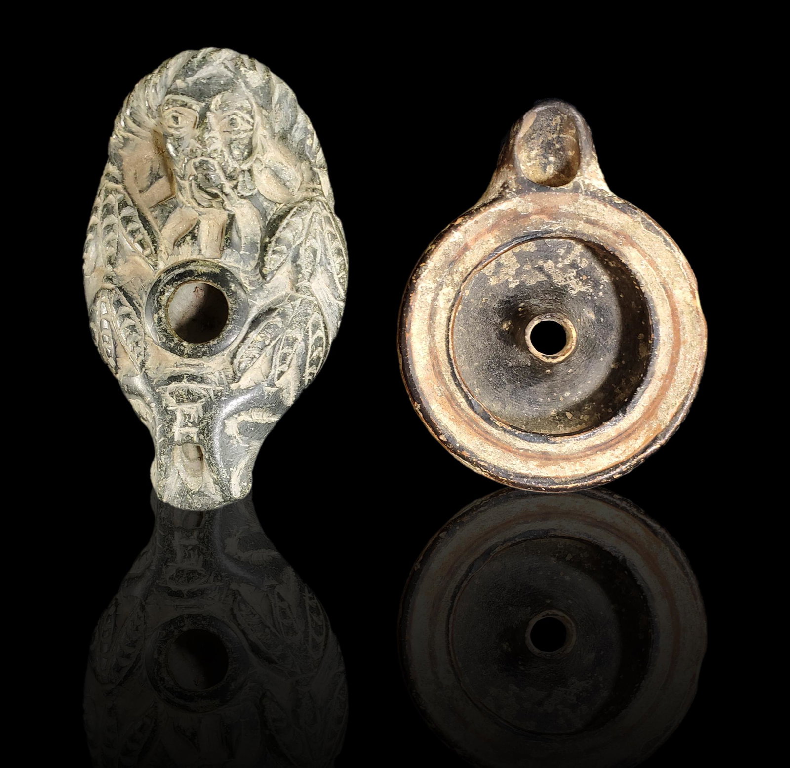 Two antique oil lamps, one Syrian the other Greek: Two old oil lamps; one Syrian the other Greek. The Syrian is carved stone, (probable catlinite), the Greek, terracotta. Measures 4" and 4 3/4" long.