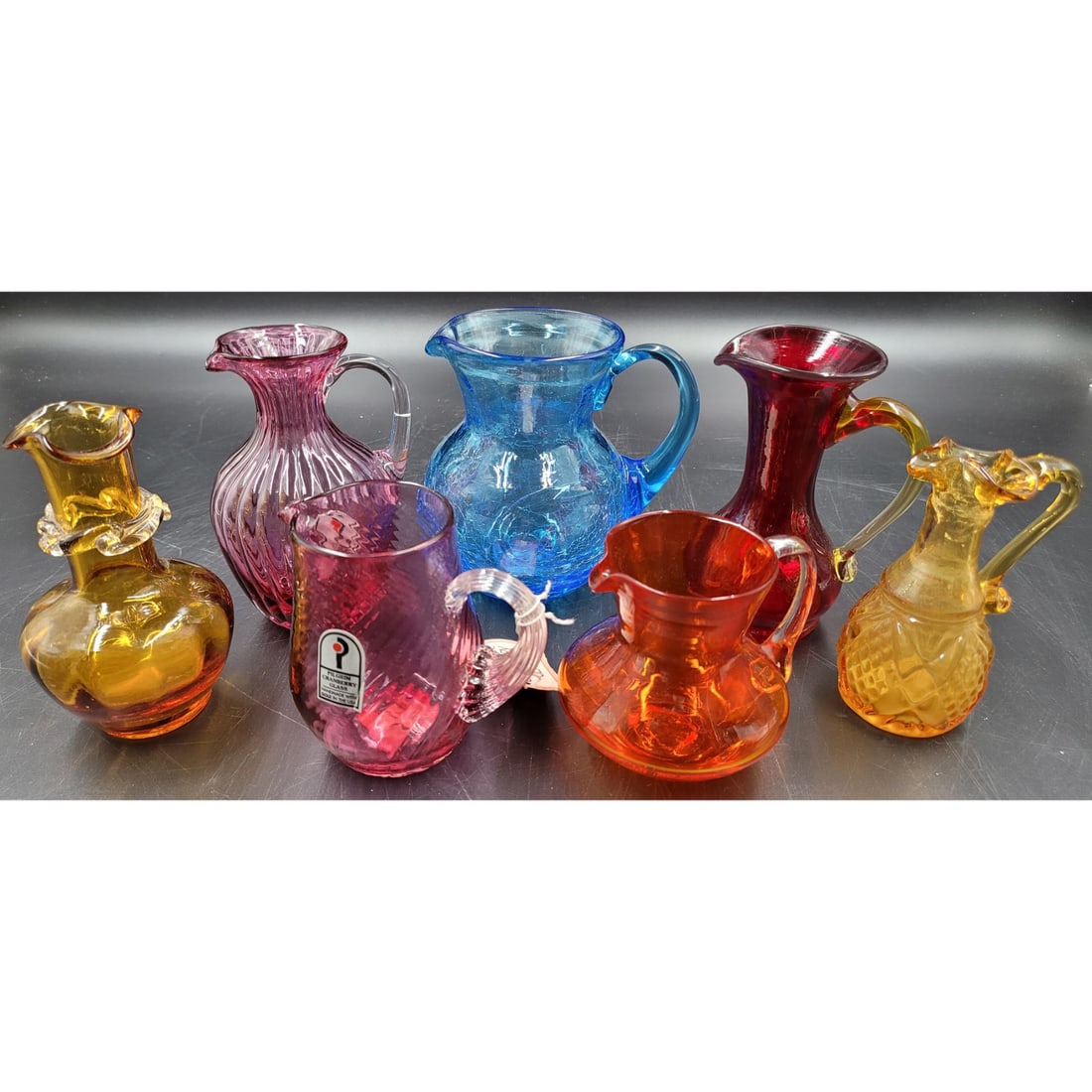 Lot of 7 Blenko and Pilgrim Cranberry Glass Small Pitchers: Lot of 7 Blenko and Pilgrim Cranberry Glass Small Pitchers. Lot includes 5 Blenko pieces and 2 Pilgrim pieces. Pitchers measure from 3.25" X 3.5 to 5" X 5" || Please carefully read our terms of sale, 